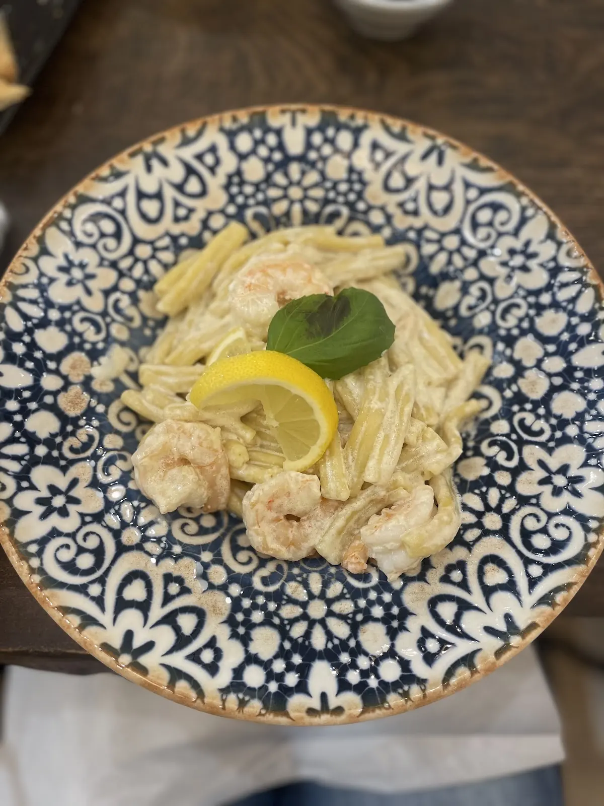 Creamy salmon tagliatelle with a lemon slice and basil on a blue-and-white patterned plate